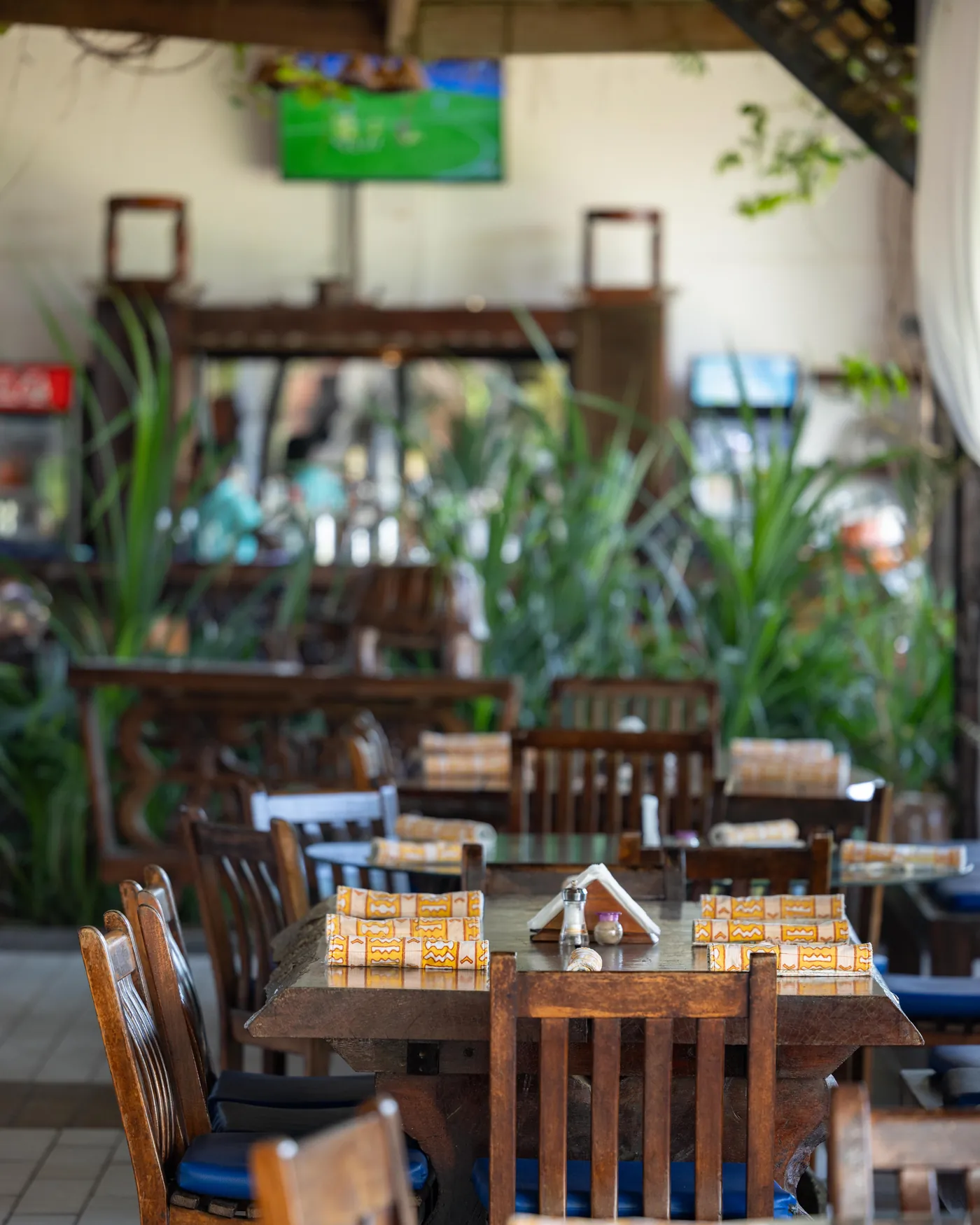 The dining room laid up for service, tables running back through the plants