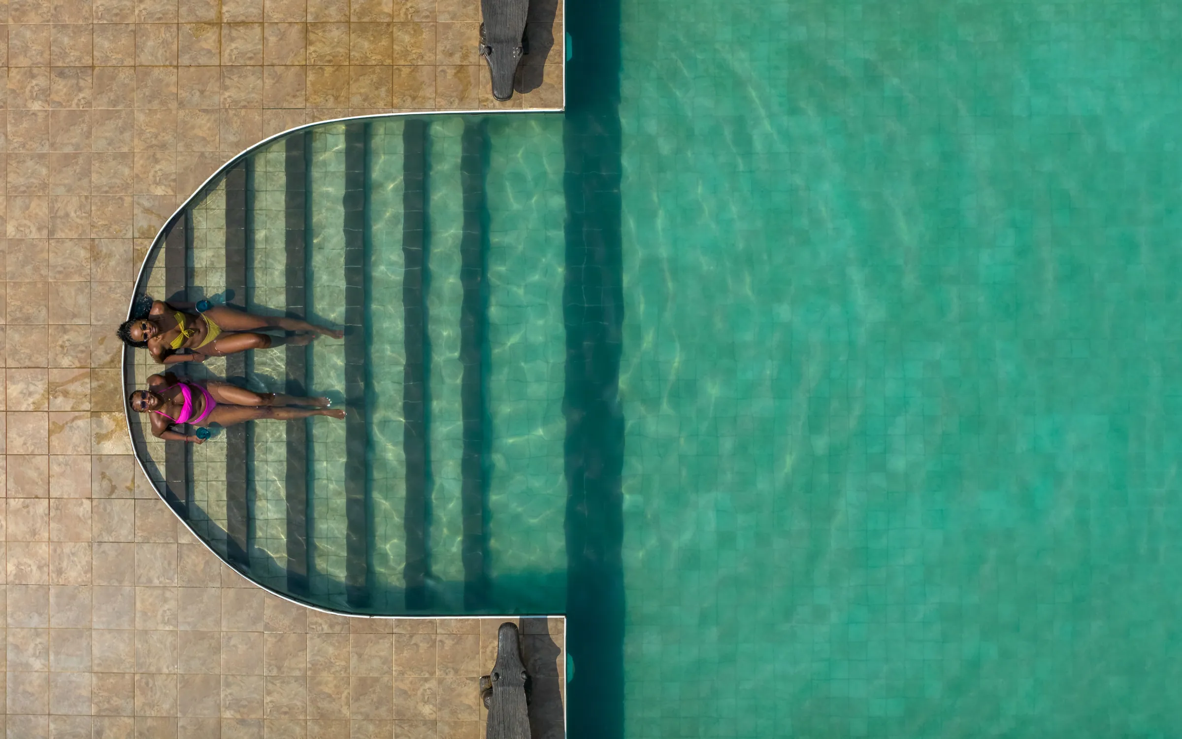 Two guests on the submerged steps of the pool, seen from above